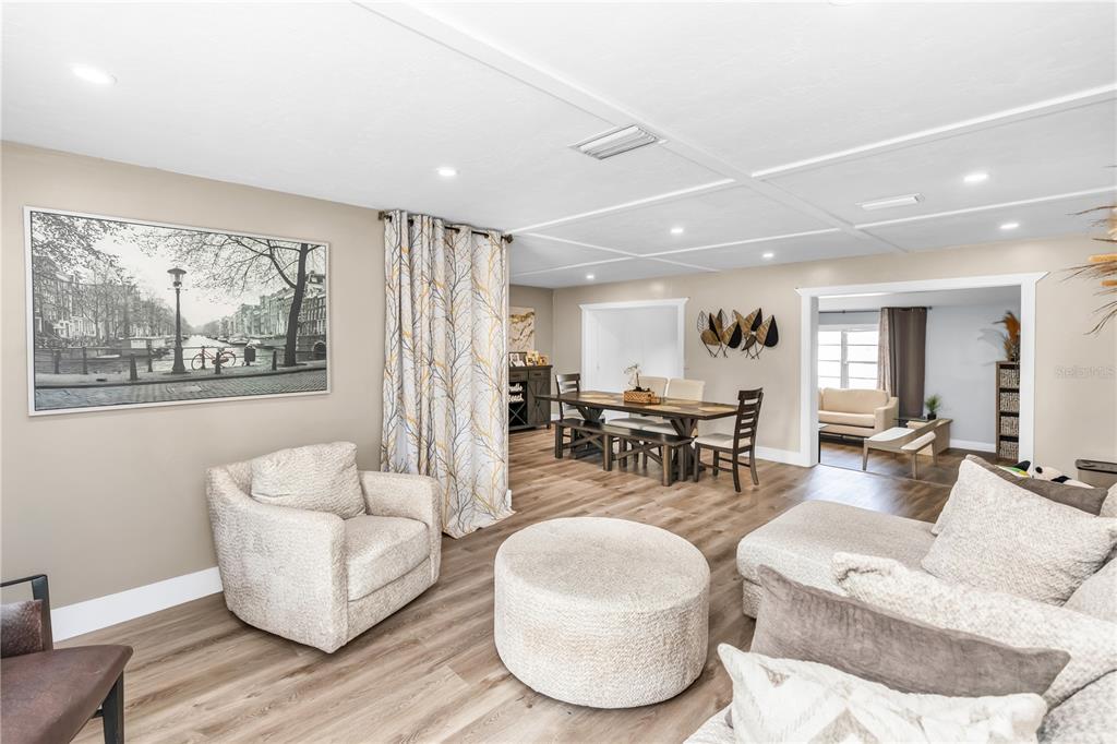 A living room and dining area feature light wood flooring, neutral walls, and modern furniture — 1020 COBBLESTONE AVENUE, DELTONA, FL