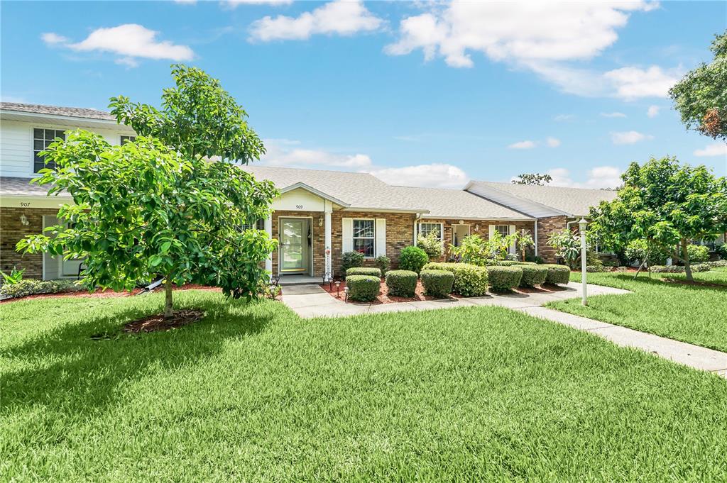 A single-story brick building with a green lawn, several trees, and a paved walkway — 909 ILLINOIS AVENUE, ST CLOUD, FL
