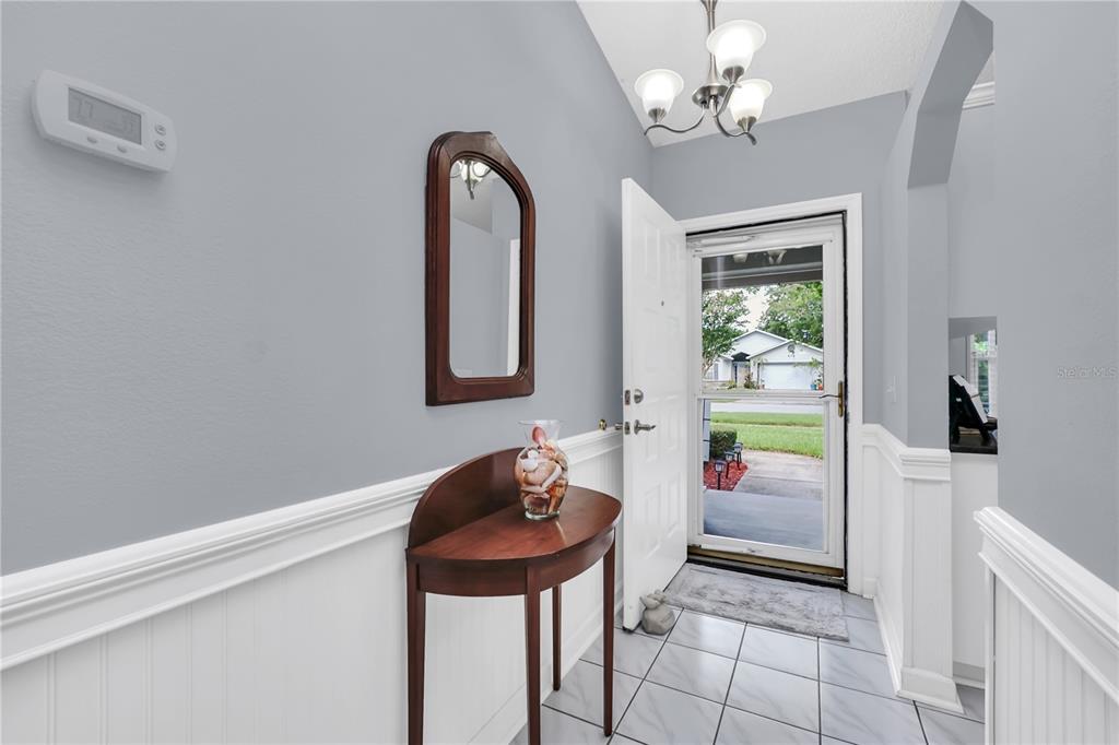 An entryway features a wood console table, a wall mirror, and a tiled floor — 909 ILLINOIS AVENUE, ST CLOUD, FL