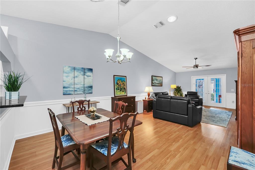A dining area with a wooden table and chairs sits adjacent to a living room — 909 ILLINOIS AVENUE, ST CLOUD, FL