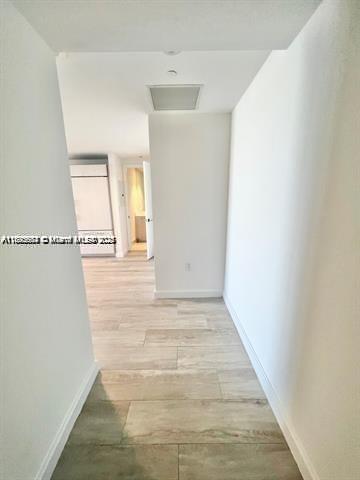 A hallway with light wood-look tile flooring leads toward an open kitchen area — 45 SW 9th St # 3009, Miami FL 33130, MIAMI, FL