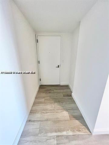 A narrow entryway features white walls, a single white door, and light wood-look tile flooring — 45 SW 9th St # 3009, Miami FL 33130, MIAMI, FL