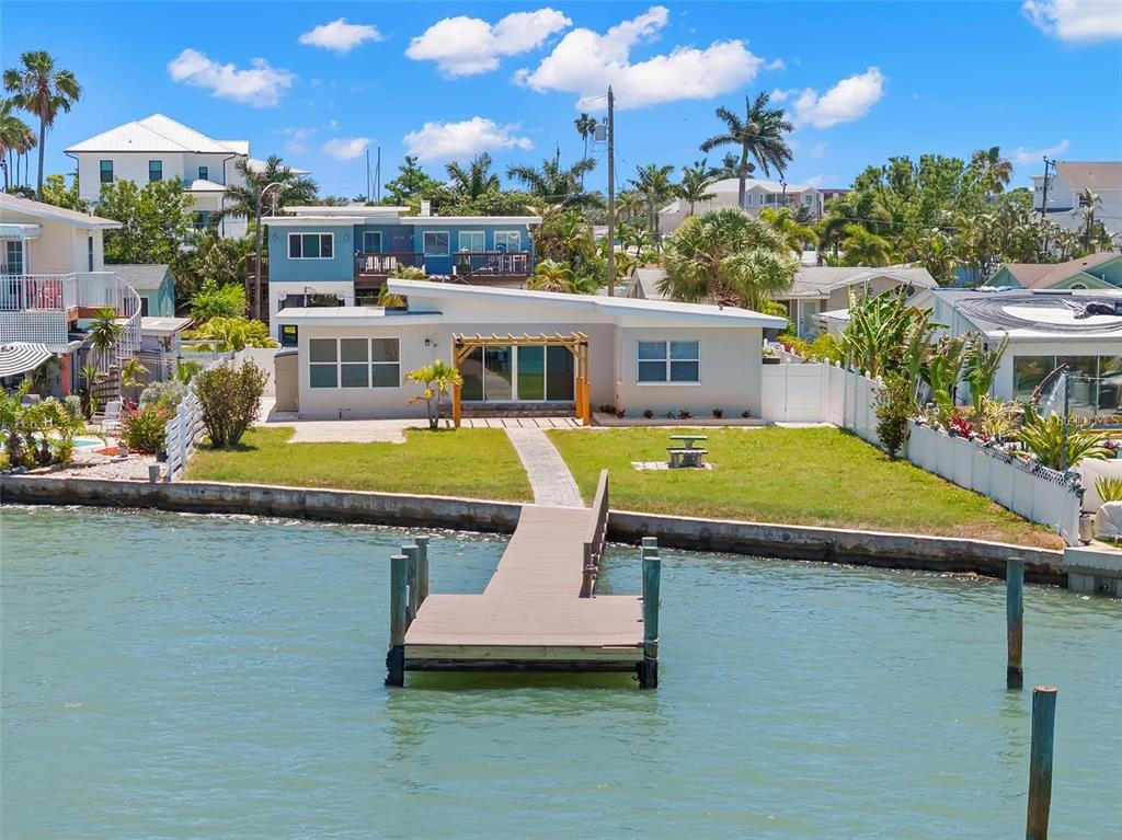 A waterfront house with a private dock, a grassy yard, and a shed roof design — 708 SUNSET COVE, MADEIRA BEACH, FL