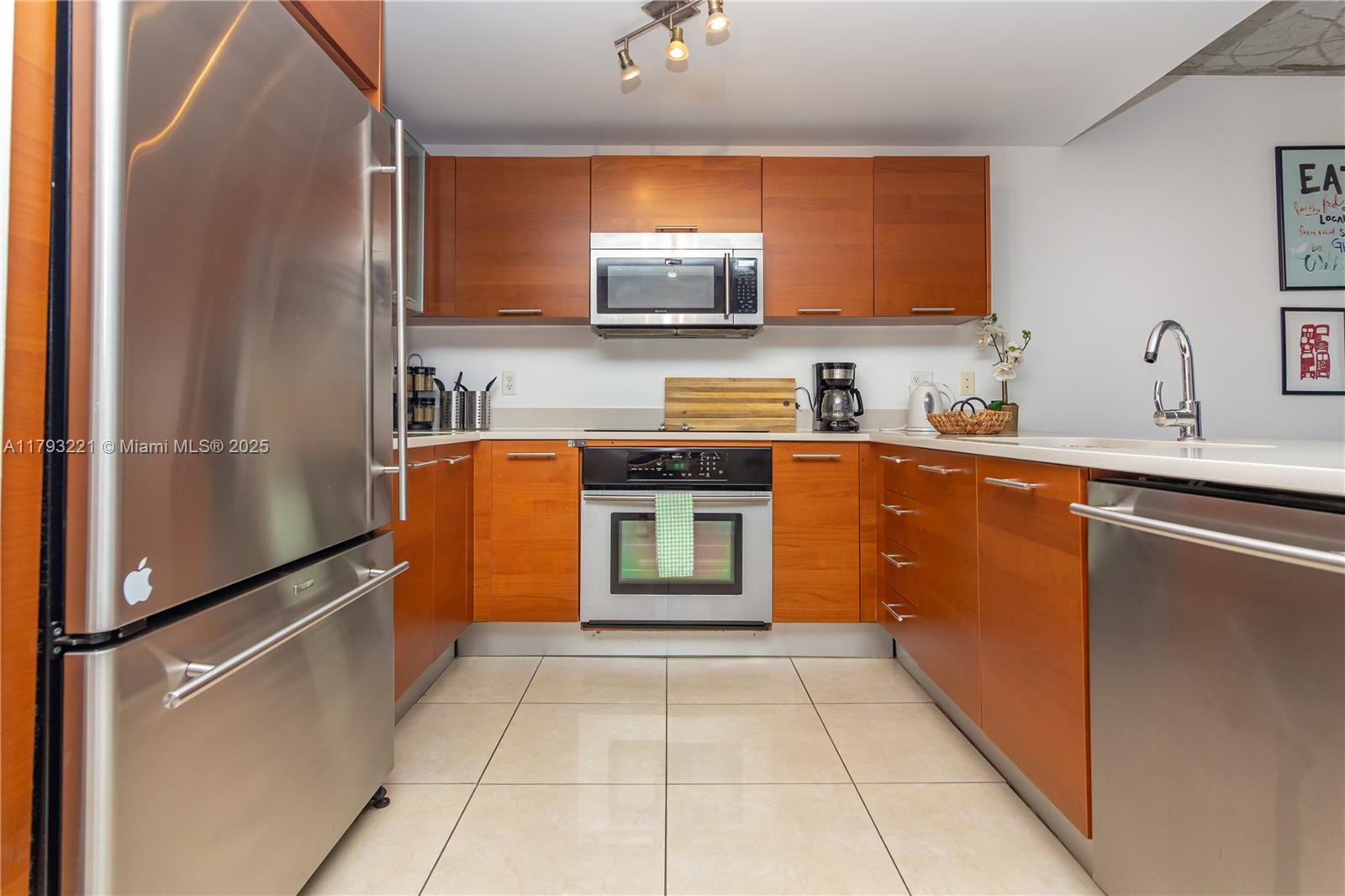 A galley kitchen features wood cabinets, stainless steel appliances, and light-colored floor tiles — 3250 NE 1st Ave # 608, Miami FL 33137, MIAMI, FL