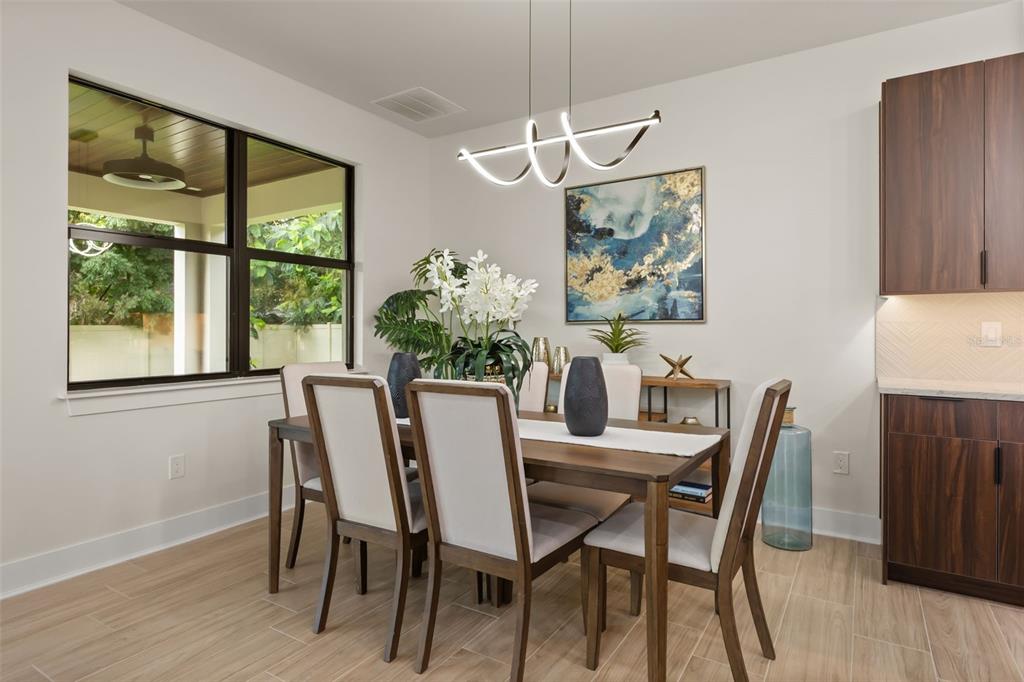A dining room features a wooden table, upholstered chairs, a modern light fixture, and dark cabinetry — 1910 CLOVERLAWN AVENUE, ORLANDO, FL