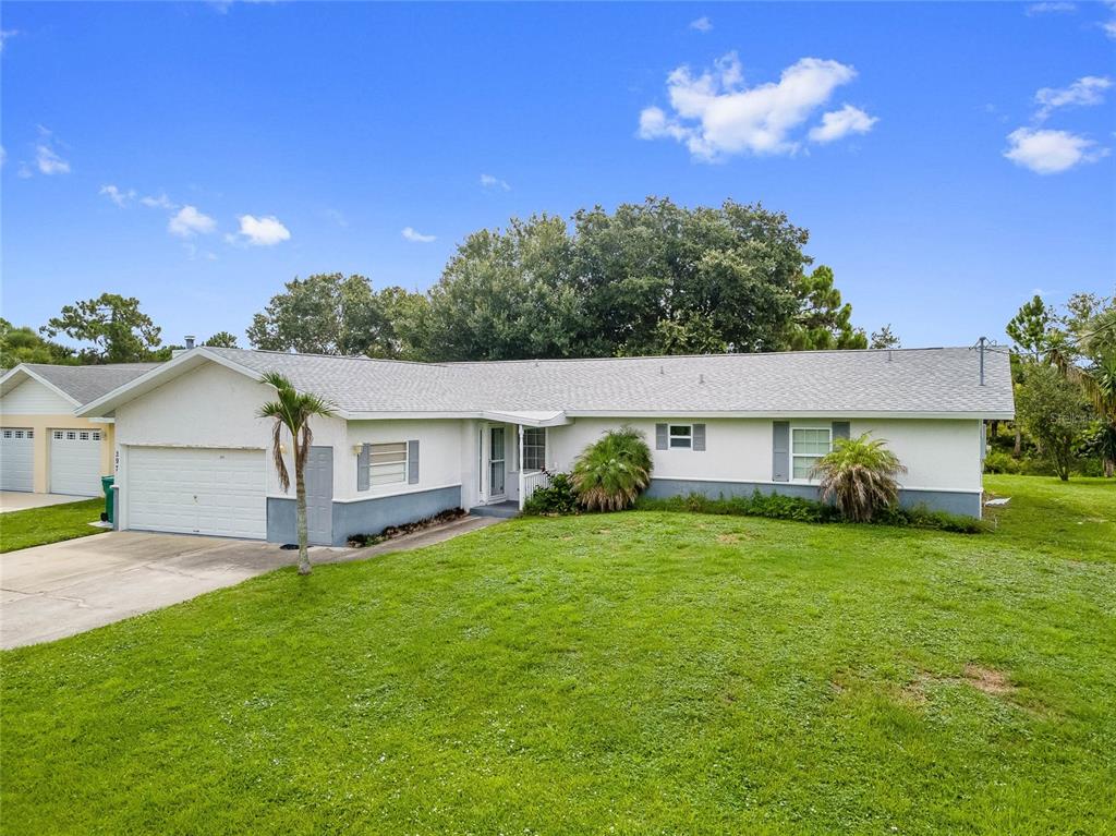 A single-story house with a white exterior, gray roof, and attached garage sits on grass — 297 CHESHIRE STREET, PORT CHARLOTTE, FL