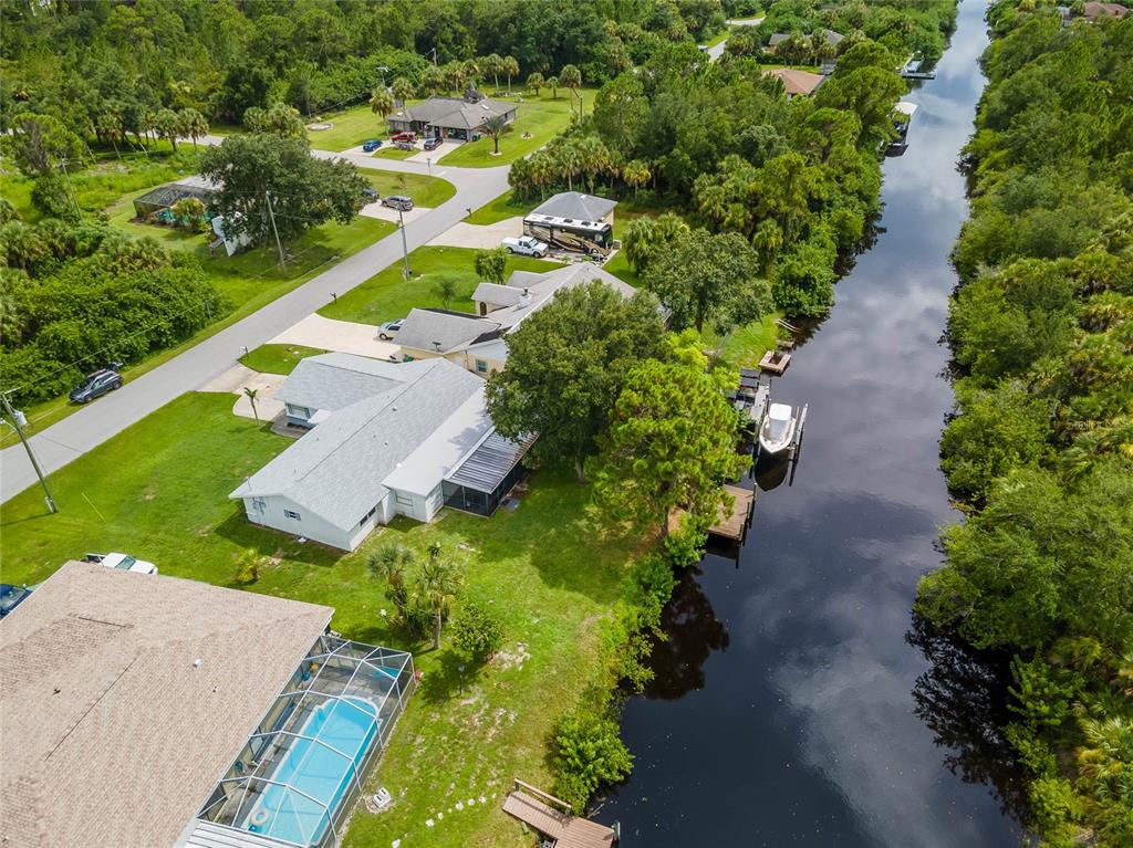 An aerial view shows a residential house with a pool and boat dock along a canal — 297 CHESHIRE STREET, PORT CHARLOTTE, FL