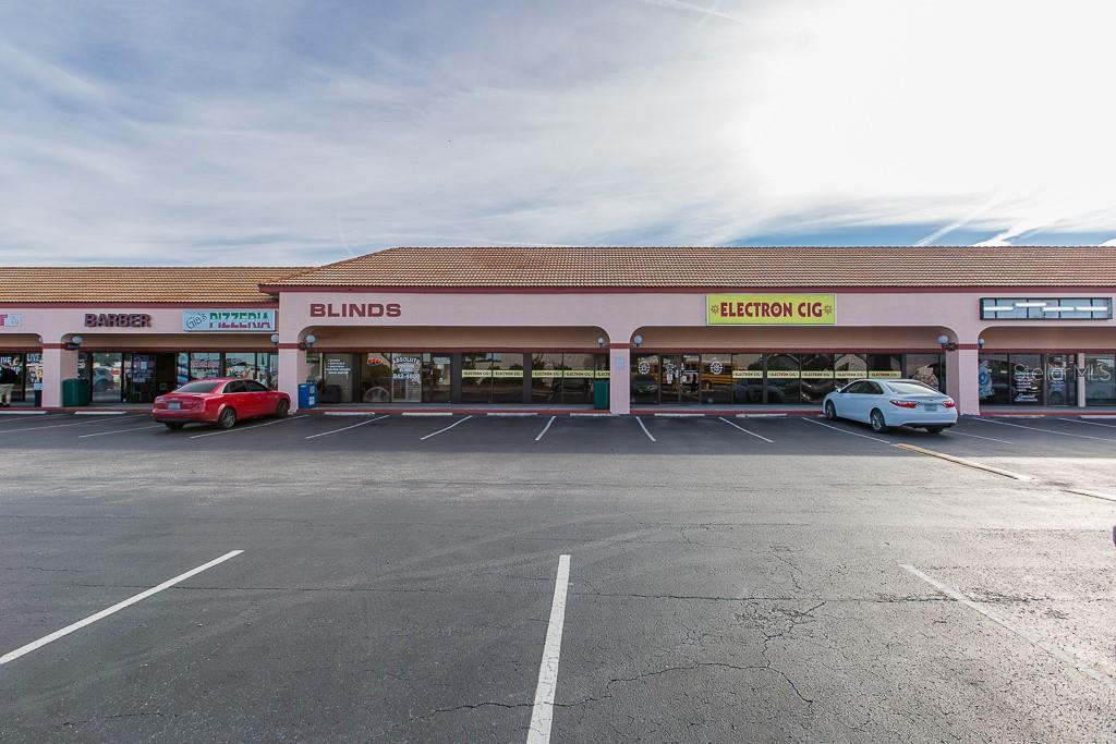 A pink commercial strip mall building with a pet shop and parking lot in front — 7200 RIDGE ROAD, PORT RICHEY, FL