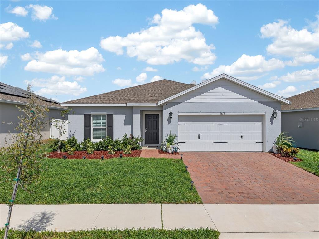 A single-story house with a gray exterior, a two-car garage, and a brick driveway — 1654 LAIA ROAD, HAINES CITY, FL
