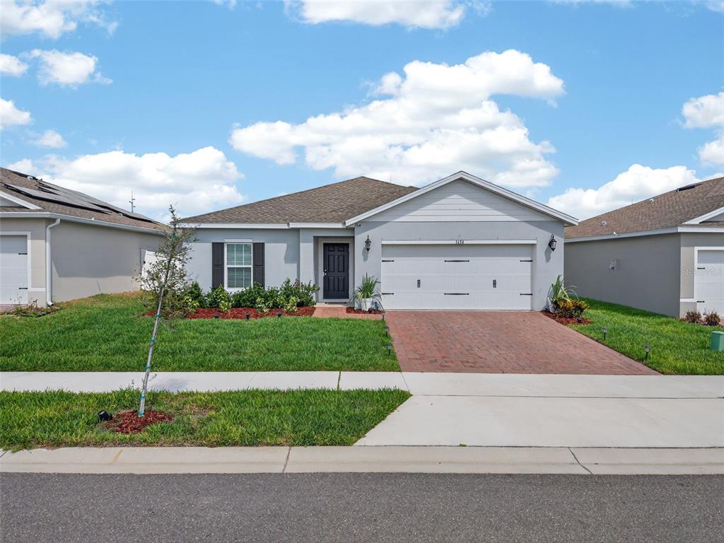 A single-story house with a gray exterior, a two-car garage, and a brick driveway — 1654 LAIA ROAD, HAINES CITY, FL