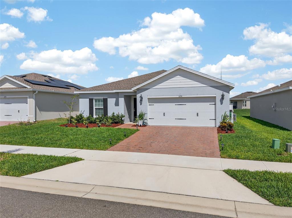 A single-story house with a gray exterior, a brick driveway, and a two-car garage — 1654 LAIA ROAD, HAINES CITY, FL