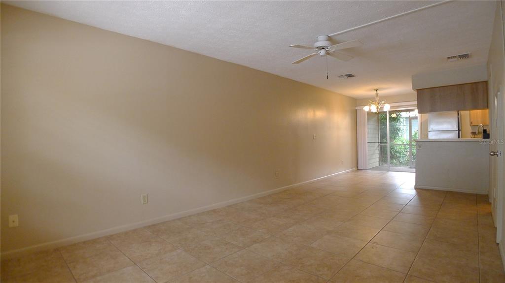 An open-concept living and dining area features beige walls, tile flooring, and a ceiling fan — 608 LYNCHBURG DRIVE, BRANDON, FL