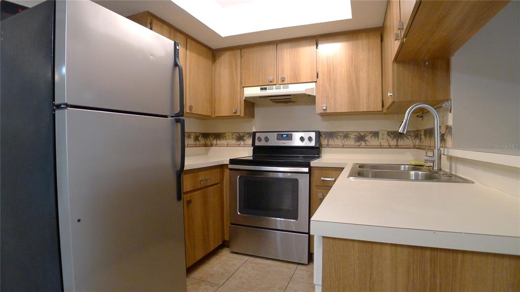 A kitchen features wood cabinets, stainless steel appliances, a double sink, and tile flooring — 608 LYNCHBURG DRIVE, BRANDON, FL