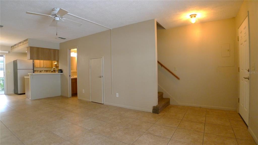 An interior view shows a tiled living area with a kitchen, staircase, and doorway — 608 LYNCHBURG DRIVE, BRANDON, FL