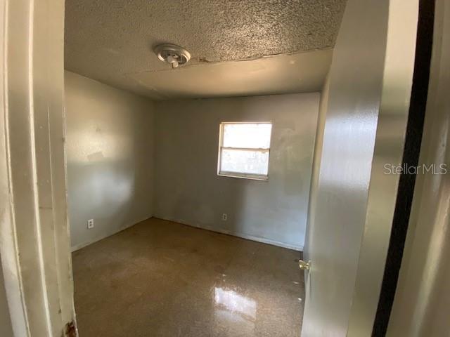 An empty bedroom features light-colored walls, a single window, and a textured ceiling — 410 TERRY STREET, WILDWOOD, FL