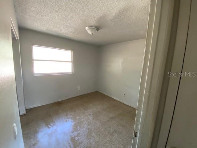 An empty bedroom with light-colored walls, a single window, and a ceiling light fixture — 410 TERRY STREET, WILDWOOD, FL