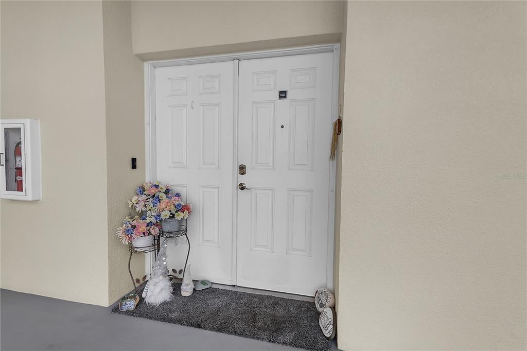 A double white front door with a floral arrangement and a welcome mat — 2801 S RIDGEWOOD AVENUE UNIT 502, SOUTH DAYTONA, FL