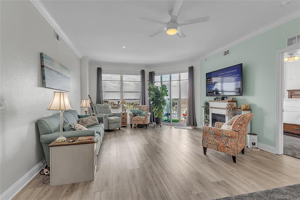 A living room features light wood-look flooring, a ceiling fan, a fireplace, and balcony access — 2801 S RIDGEWOOD AVENUE UNIT 502, SOUTH DAYTONA, FL