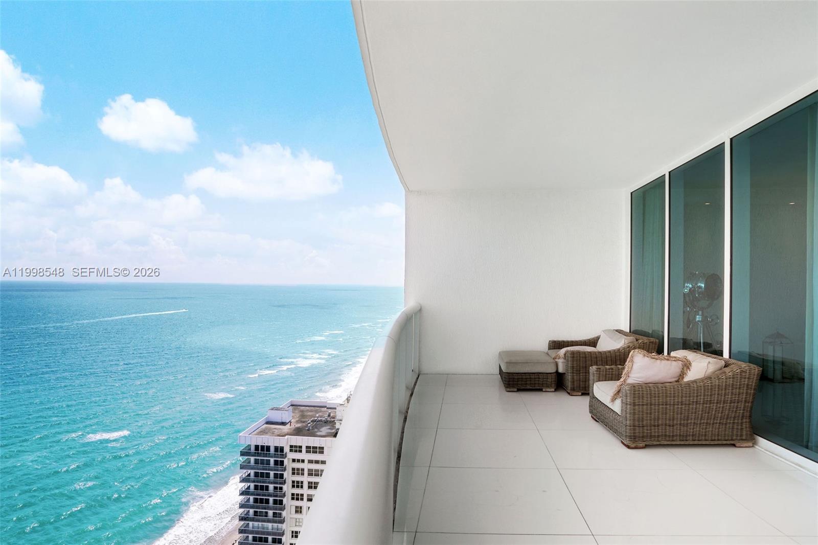 A high-rise balcony features white tile flooring, wicker lounge chairs, and a panoramic ocean view — 2711 S Ocean Dr # 2803, Hollywood FL 33019, HOLLYWOOD, FL