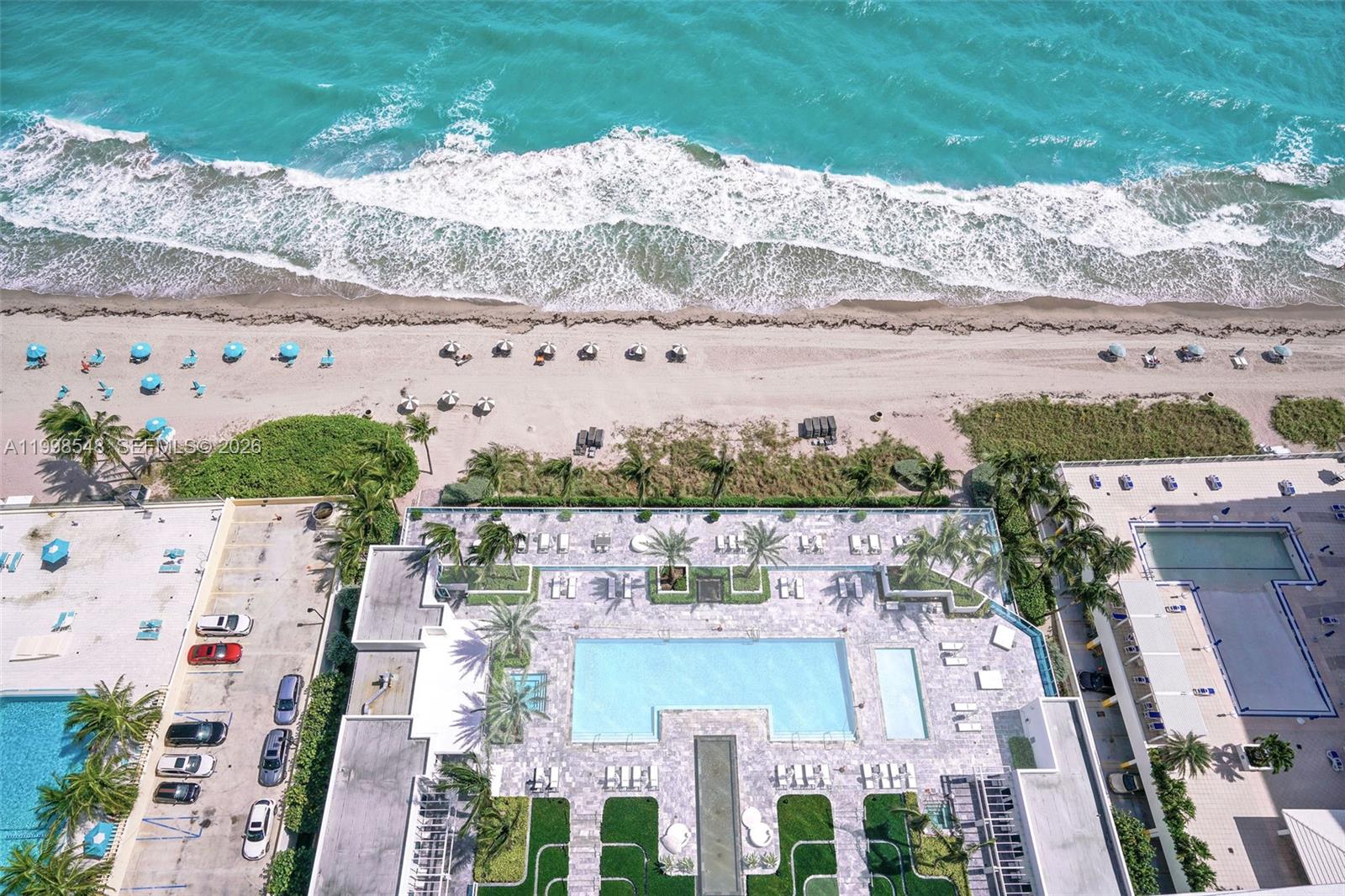An aerial view shows a swimming pool deck, parking area, and beach along the ocean — 2711 S Ocean Dr # 2803, Hollywood FL 33019, HOLLYWOOD, FL