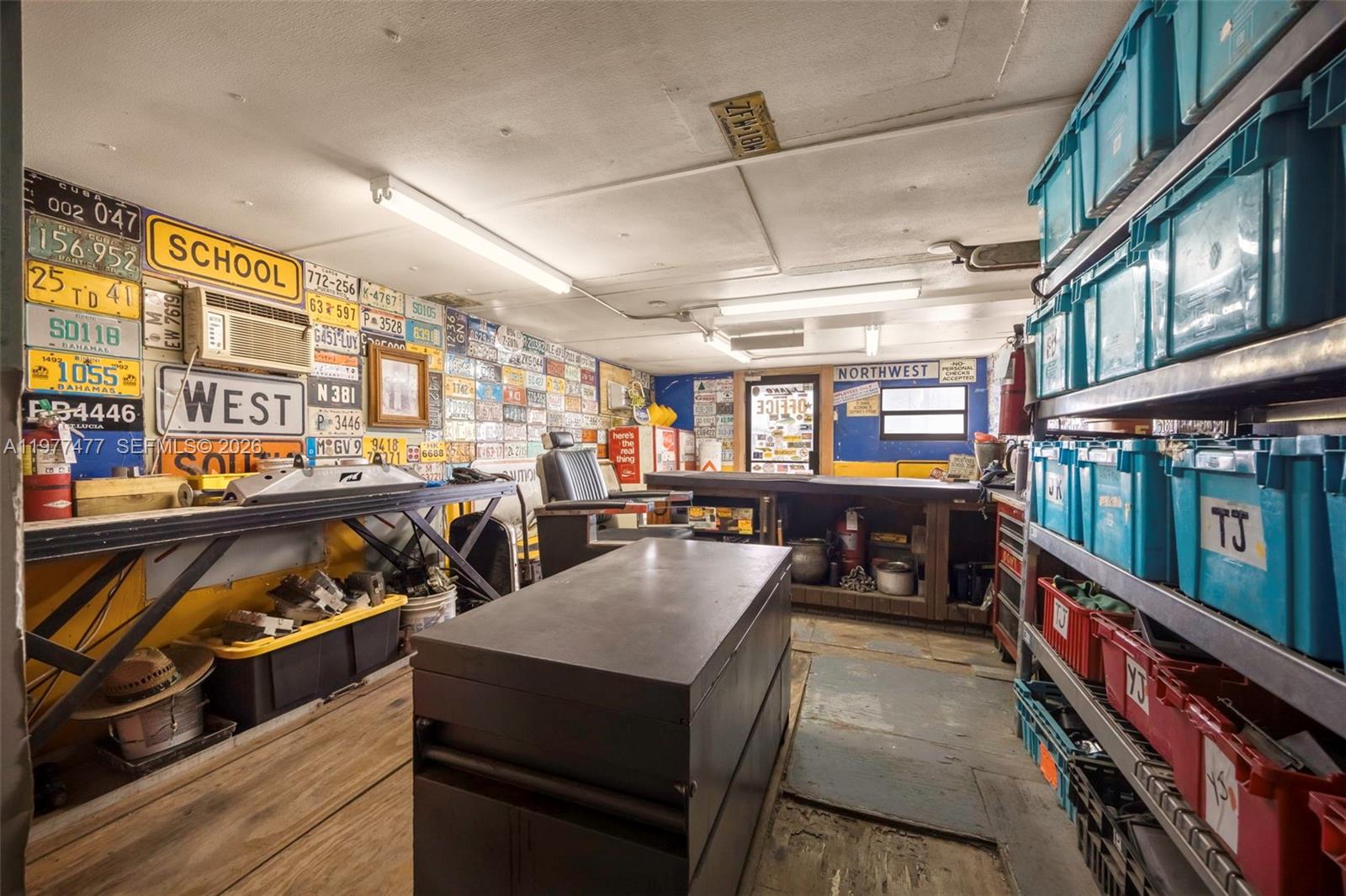 A workshop or storage room features walls covered in license plates and metal shelving units — 12880 Port Said Rd, Opa-Locka FL 33054, OPA-LOCKA, FL