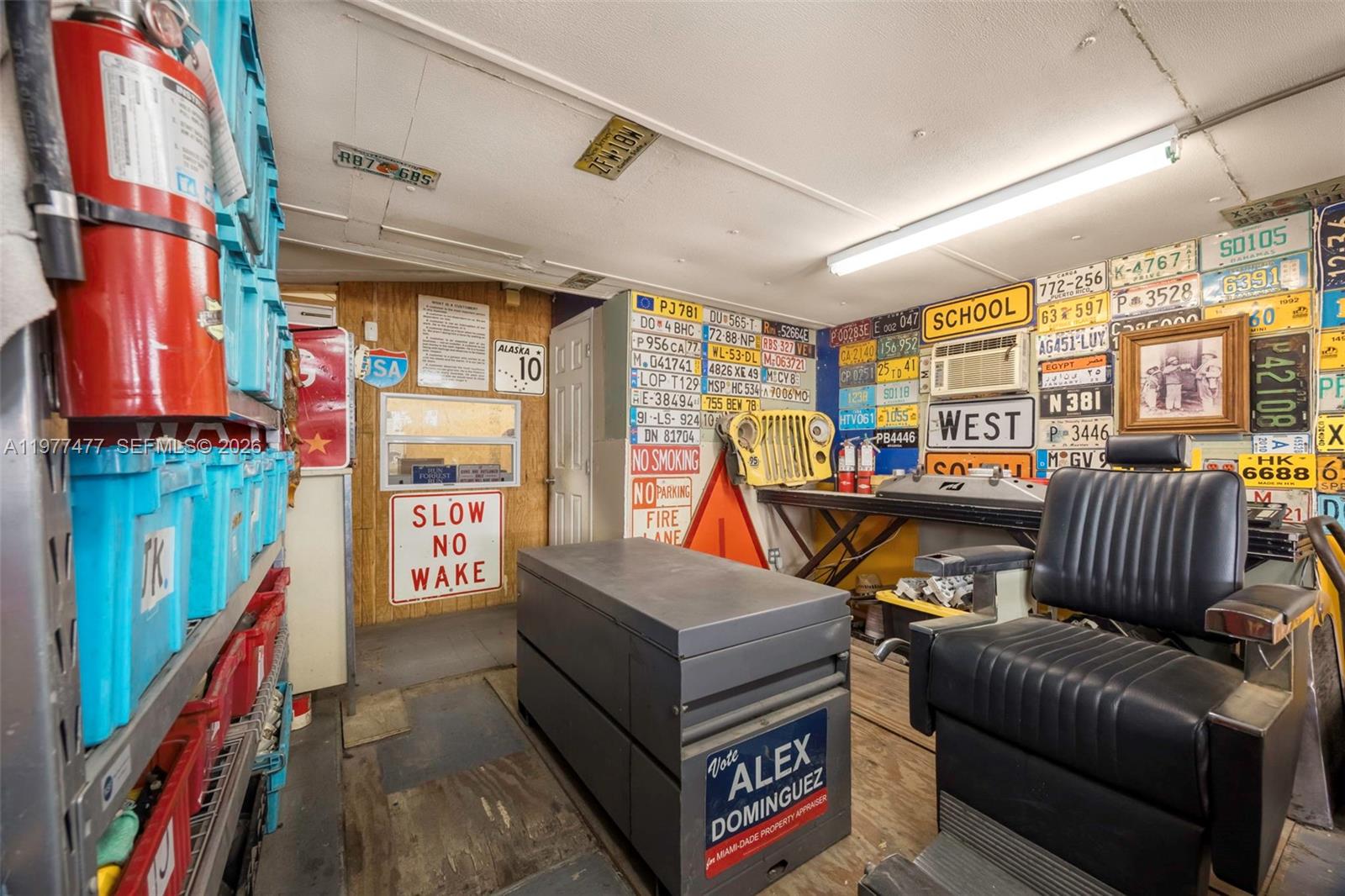 A cluttered garage or workshop features walls covered in numerous vintage license plates and signs — 12880 Port Said Rd, Opa-Locka FL 33054, OPA-LOCKA, FL