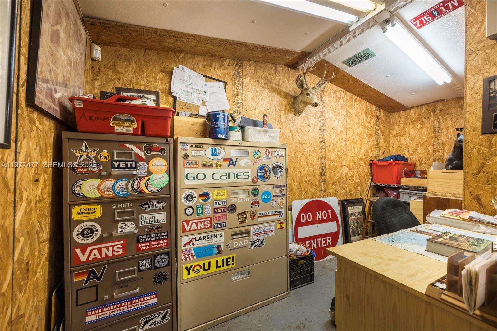 A storage room features OSB walls, two sticker-covered metal filing cabinets, and a deer head mount — 12880 Port Said Rd, Opa-Locka FL 33054, OPA-LOCKA, FL