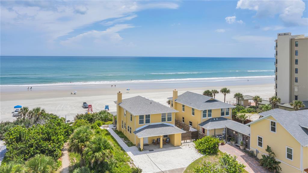 An aerial view shows yellow houses near a sandy beach and the ocean — 2101 HILL STREET, NEW SMYRNA BEACH, FL