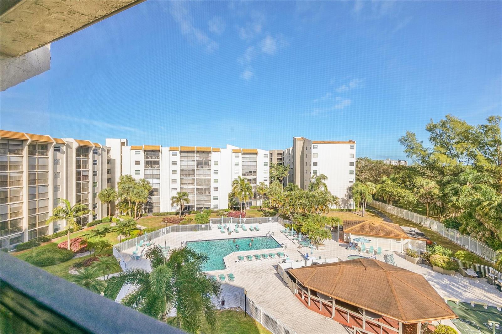 An elevated view of a swimming pool area surrounded by multi-story apartment buildings and palm trees — 3920 Inverrary Boulevard # c, Lauderhill FL 33319, LAUDERHILL, FL