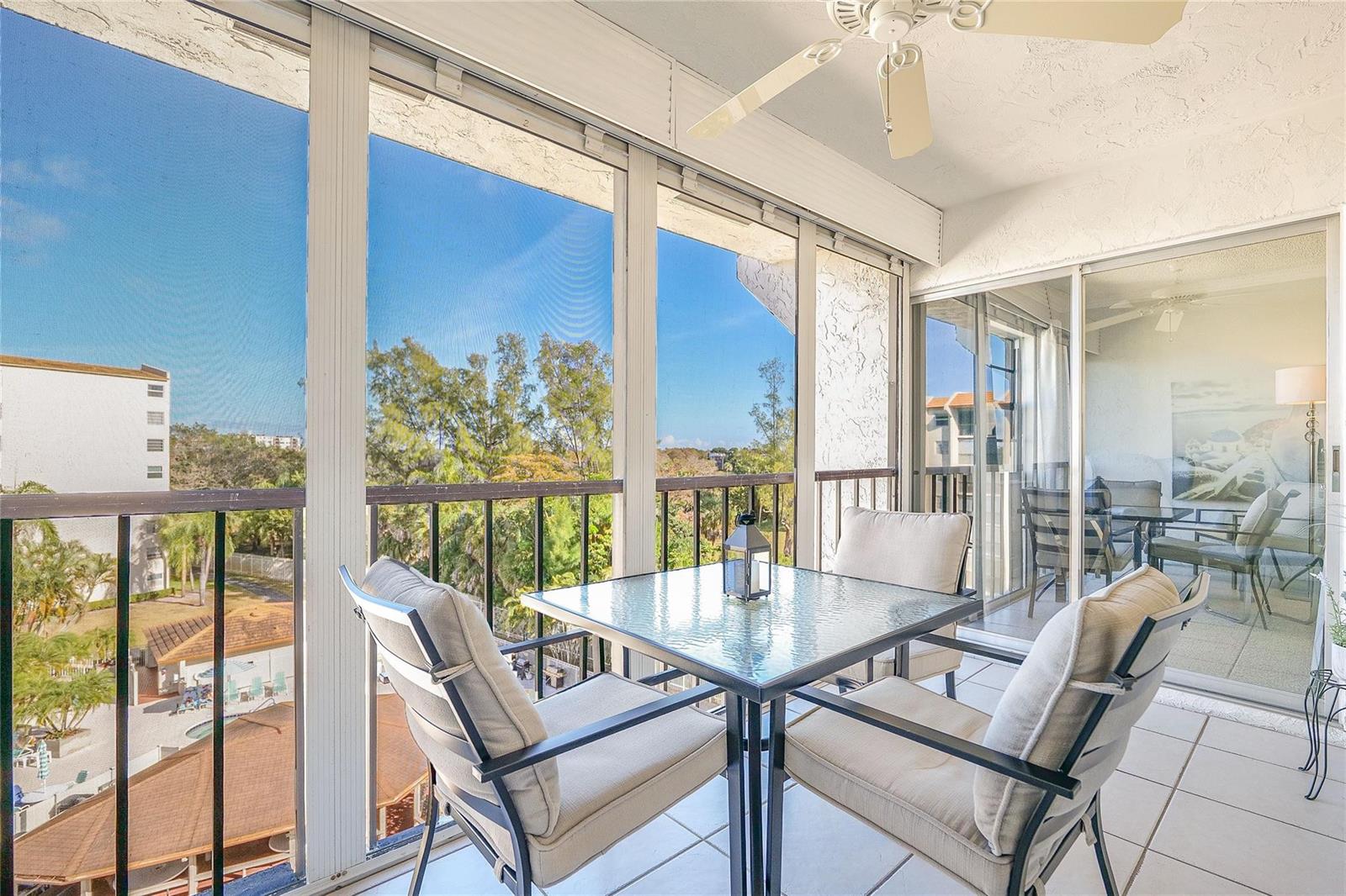 A screened-in balcony features a glass-top table, chairs, tile flooring, and a ceiling fan — 3920 Inverrary Boulevard # c, Lauderhill FL 33319, LAUDERHILL, FL