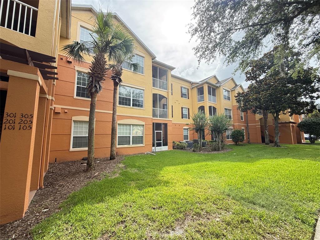 A three-story apartment building with yellow and orange stucco walls and palm trees — 6380 CONTESSA DRIVE UNIT 303, ORLANDO, FL