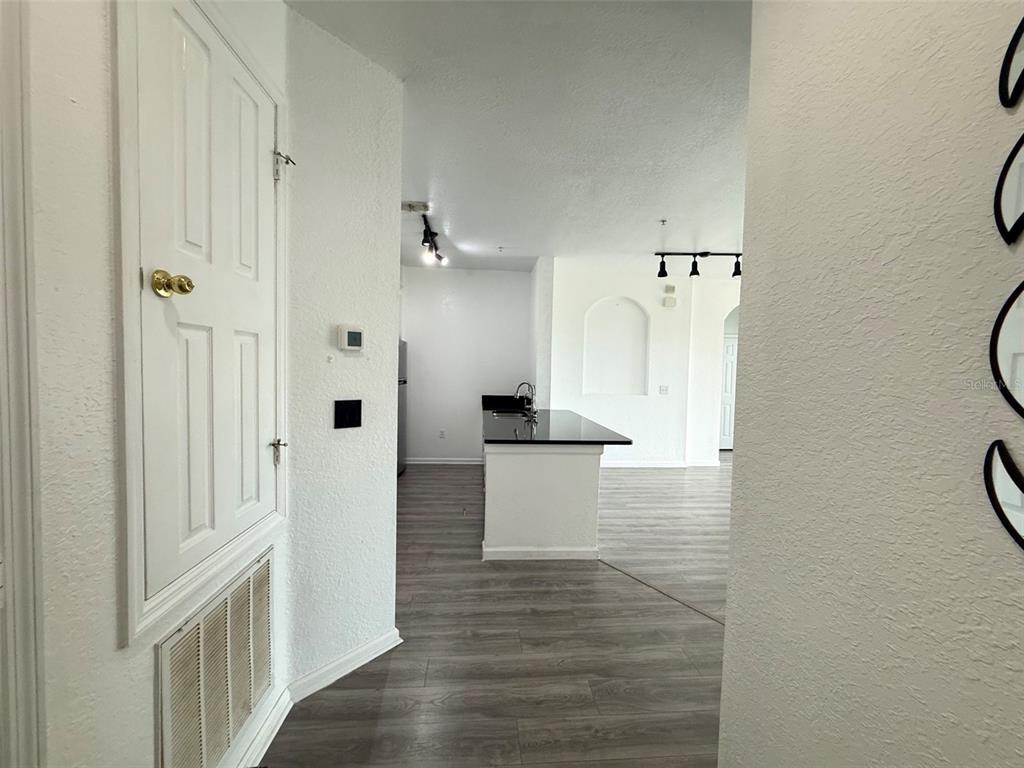 A view from a hallway looking into a kitchen with a black island countertop — 6380 CONTESSA DRIVE UNIT 303, ORLANDO, FL
