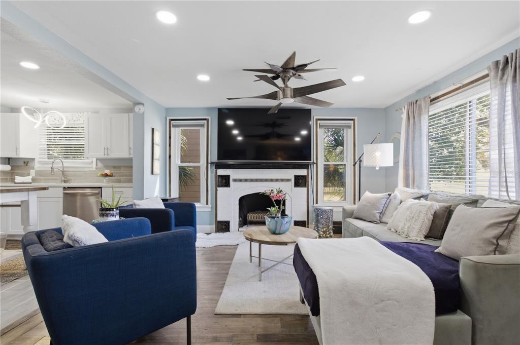 A living room features a fireplace with a mounted television, blue armchairs, and a sofa — 4831 FAIRFIELD AVENUE S, ST PETERSBURG, FL