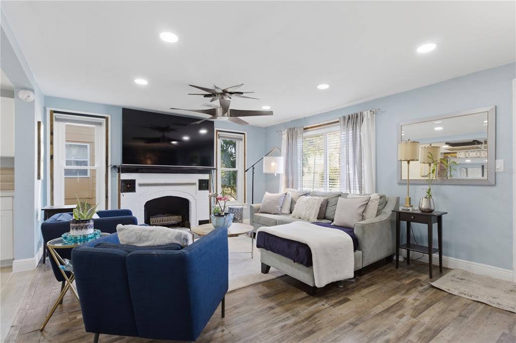 A living room features a fireplace, a large television, blue armchairs, and a gray sectional — 4831 FAIRFIELD AVENUE S, ST PETERSBURG, FL