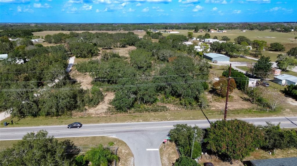 An aerial view shows a wooded lot bordering a paved road with a stop sign — JOHNSON AVENUE E, HAINES CITY, FL
