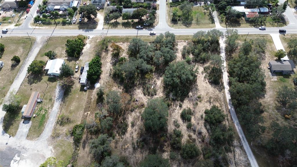 An aerial view shows a large, partially wooded vacant lot situated between two residential properties — JOHNSON AVENUE E, HAINES CITY, FL