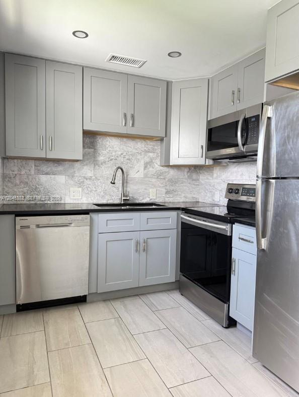 A kitchen features light gray cabinets, stainless steel appliances, and a marble-patterned tile backsplash — 165 Fanshaw D # 165, Boca Raton FL 33434, BOCA RATON, FL