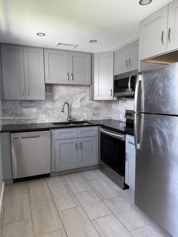 A kitchen features gray cabinets, stainless steel appliances, and a marble-patterned backsplash — 165 Fanshaw D # 165, Boca Raton FL 33434, BOCA RATON, FL