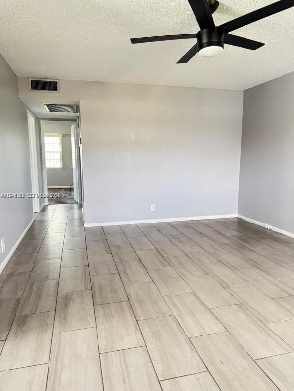 An empty room features light-colored tile flooring, gray walls, and a black ceiling fan — 165 Fanshaw D # 165, Boca Raton FL 33434, BOCA RATON, FL