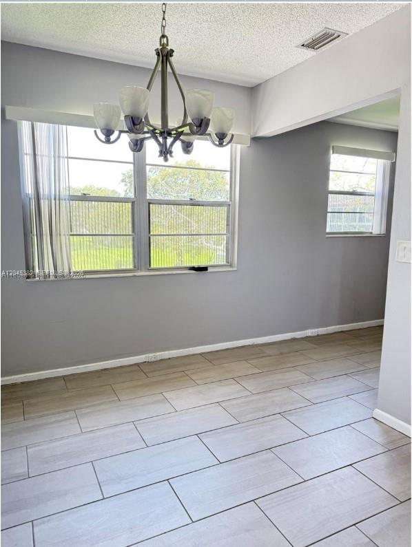 A dining area features light gray walls, wood-look tile flooring, and a modern chandelier — 165 Fanshaw D # 165, Boca Raton FL 33434, BOCA RATON, FL