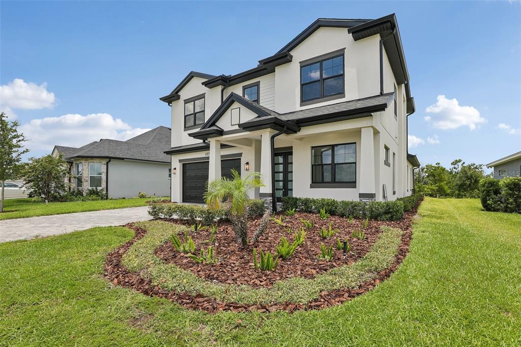 A two-story house with a white exterior, dark trim, and a landscaped front yard — 485 ADAMS VIEW LANE, AUBURNDALE, FL