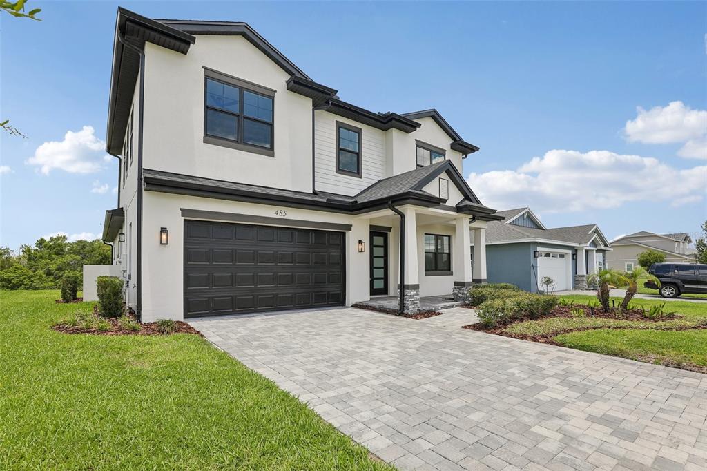 A two-story house with a white stucco facade, black trim, and a paved driveway — 485 ADAMS VIEW LANE, AUBURNDALE, FL