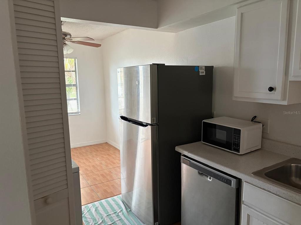 A kitchen features a stainless steel refrigerator, a white microwave, and a tiled dining area — 2320 MARGARITA COURT UNIT 2320, KISSIMMEE, FL