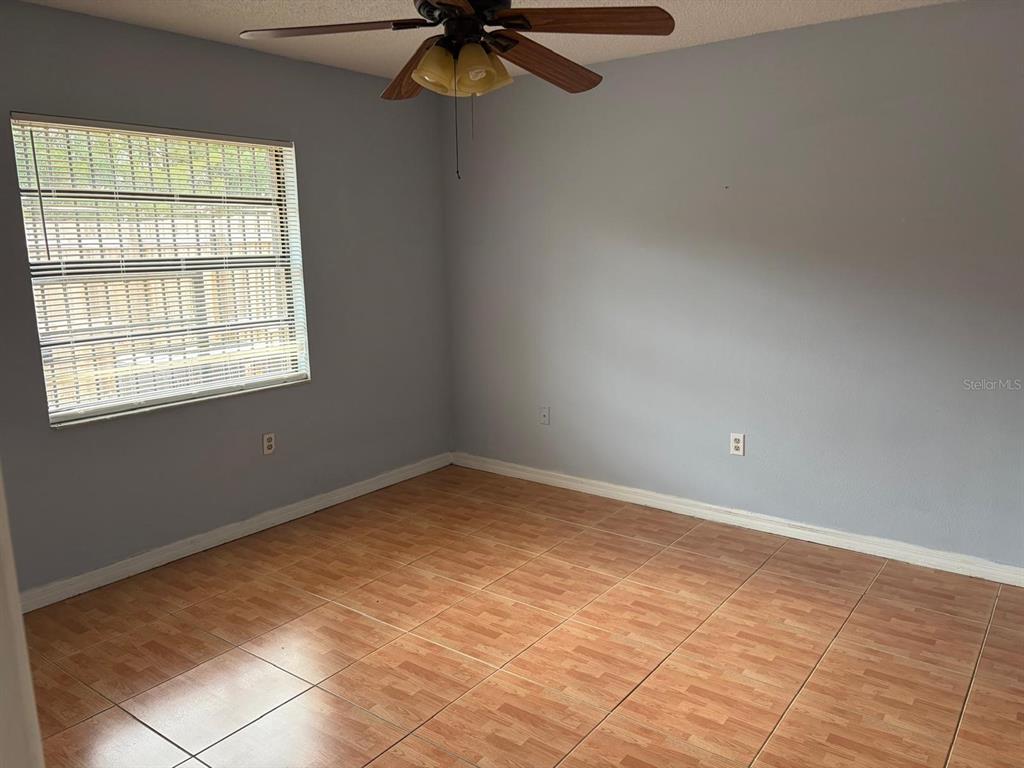 An empty room features light blue walls, wood-look tile flooring, and a ceiling fan — 2320 MARGARITA COURT UNIT 2320, KISSIMMEE, FL