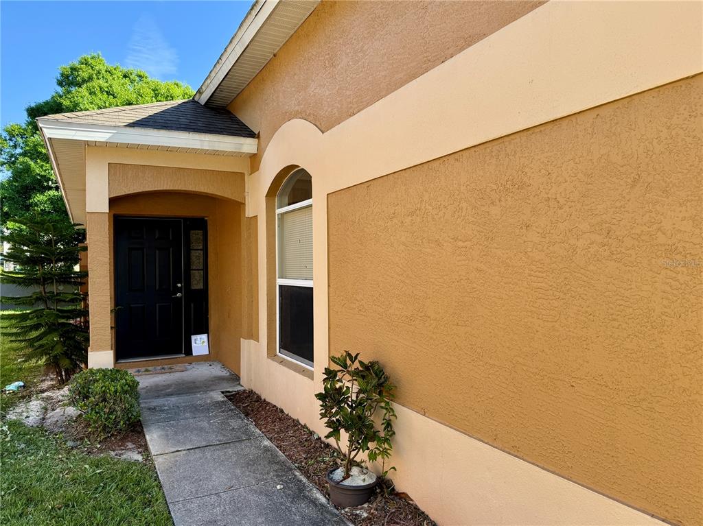 A tan stucco house exterior features a black front door and an arched window — 112 PEREGRINE COURT, WINTER SPRINGS, FL