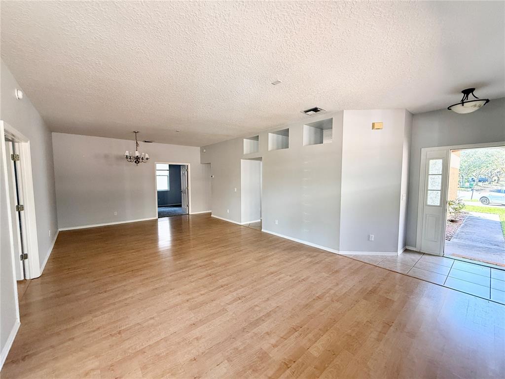 An open-concept living area features light wood-look flooring, gray walls, and a tiled entryway — 112 PEREGRINE COURT, WINTER SPRINGS, FL