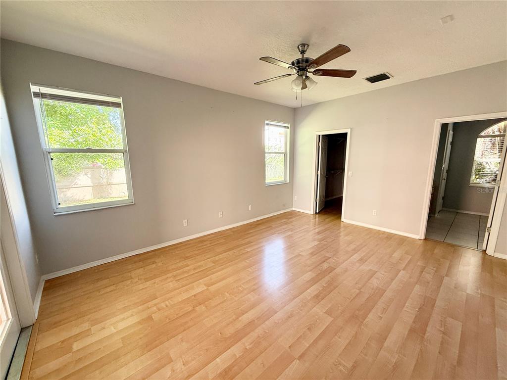 An empty bedroom features light gray walls, wood-look flooring, a ceiling fan, and two windows — 112 PEREGRINE COURT, WINTER SPRINGS, FL