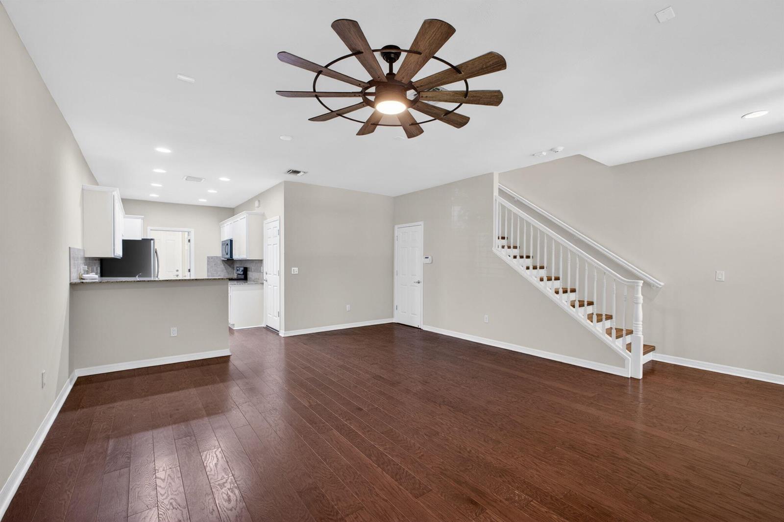 An open-concept living area features dark hardwood floors, a ceiling fan, and a staircase — 1126 Dakota Drive, Jupiter FL 33458, JUPITER, FL