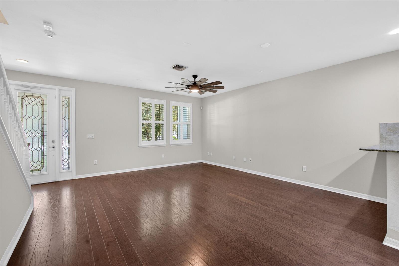 An empty living room features dark hardwood floors, light gray walls, and a ceiling fan — 1126 Dakota Drive, Jupiter FL 33458, JUPITER, FL