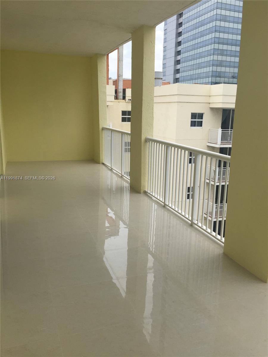 A covered balcony features light-colored tile flooring and white metal railings overlooking nearby buildings — 170 SE 14th St # 3005, Miami FL 33131, MIAMI, FL